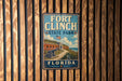 A vintage-style metal sign for Fort Clinch State Park in Florida, featuring an illustration of the fort and surrounding landscape.