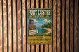 A vintage-style metal sign for the Fort Custer Recreation Area in South West Michigan, featuring a beach scene and a lighthouse.