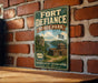 A vintage-style metal sign for Fort Defiance State Park, featuring a scenic illustration of the park's landscape and a castle.