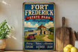 A vintage-style metal sign for Fort Frederick State Park in Maryland, featuring a castle, cannon, and a scenic landscape.