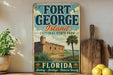 A vintage-style sign for Fort George Island, Florida, featuring a castle, palm trees, and a body of water.