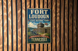 A vintage-style metal sign for Fort Loudoun State Historic Park in Tennessee, featuring a castle and a cannon, mounted on a wooden wall.