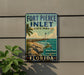 A vintage-style sign for Fort Pierce Inlet State Park in Florida, featuring a beach scene with a lighthouse and palm trees.