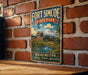 A vintage-style metal sign for Fort Simcoe State Park in Washington, featuring a castle, mountains, and a river, mounted on a brick wall.