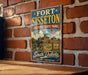 A vintage-style sign for Fort Sisset, Historic State Park, featuring an illustration of a cannon and a building, mounted on a brick wall.