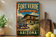 A vintage-style sign for Fort Verde State Historic Park in Arizona, featuring a wooden cabin and desert landscape.