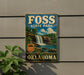 A vintage-style sign for Foss State Park in Oklahoma, featuring a waterfall and lush greenery, is displayed on a wall.