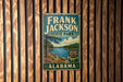 A vintage metal sign for Frank Jackson State Park in Alabama, featuring a scenic landscape with a lake and pine trees.