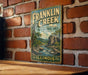 A vintage Franklin Creek sign is displayed on a brick wall, featuring a scenic illustration of the natural area.
