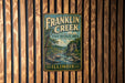 A vintage Franklin Creek sign is displayed on a wooden wall, indicating the location as the State Natural Area in Illinois.