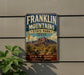 A vintage Franklin Mountains State Park sign is displayed on a wall, featuring a scenic illustration of the park's landscape with mountains, desert, and desert plants.