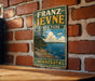 A vintage-style metal sign for Franz Jevne State Park in Minnesota, featuring a scenic landscape with a lake and mountains.