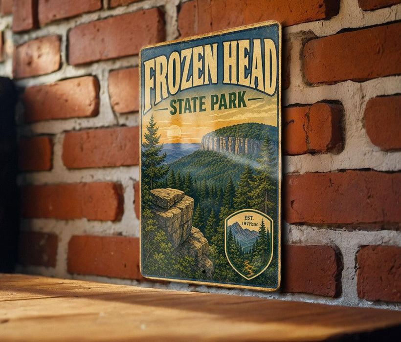 A vintage-style sign for Frozen Head State Park, featuring a scenic mountain landscape with pine trees and a sunset in the background.