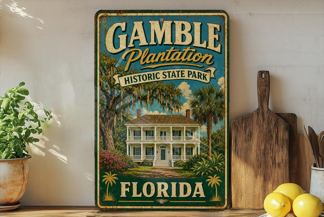 A vintage-style metal sign for Gamble Plantation Historic State Park in Florida, featuring a large illustration of a historic house surrounded by palm trees and other tropical foliage.