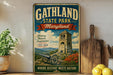 A vintage-style metal sign for Gathland State Park, Maryland, featuring a castle, a tower, and a landscape with mountains and flowers.