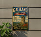 A vintage metal sign for Gathland State Park in Maryland, featuring a castle, flowers, and a cannon, mounted on a gray wall.