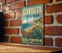 A vintage-style metal sign for Gaviota State Park in California, featuring a scenic landscape with mountains, cliffs, and a desert landscape.