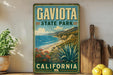A vintage-style metal sign for Gaviota State Park in California, featuring a scenic coastal landscape with mountains, ocean, and desert vegetation.