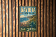 A vintage metal sign for Gavito State Park in California, featuring a scenic landscape with mountains, cliffs, and a beach.