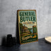 A vintage-style metal sign for General Butler State Resort Park in Kentucky, featuring a house and a river, is displayed on a gray countertop.