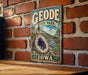 A vintage-style sign for Geode State Park in Iowa, featuring a large geode and a scenic landscape.