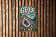 A vintage metal sign for Geode State Park in Iowa, featuring a large geode and a scenic landscape.