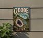 A vintage-style metal sign for Geode State Park in Iowa, featuring a large purple geode and a scenic landscape.