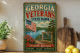 A vintage-style sign for Georgia Veterans State Park, featuring an American flag, a scenic landscape, and the text "Honor Service Sacrifice Cordele, Georgia EXPLORE * RELAX * REMEMBER".