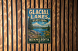 A vintage-style metal sign for Glacier Lakes State Park in Minnesota, featuring a scenic landscape with a lake, mountains, and pine trees.