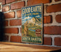 A vintage-style metal sign for Good Earth State Park in South Dakota, featuring a prairie badland landscape with a prairie dog.
