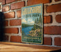 A vintage-style metal sign for Gouldsboro State Park in Pennsylvania, featuring a scenic landscape with a lake and pine trees.