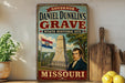 A vintage-style metal sign for Daniel Dunklin's grave, which is a state historic site in Missouri. The sign features an illustration of a monument and a portrait of a man, along with the text "GOVERNOR DANIEL DUNKLIN'S GRAVE STATE HISTORIC SITE MISSOURI".