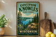 A vintage-style sign for Governor Knowles State Forest in Wisconsin, featuring a scenic landscape with pine trees, a lake, and mountains.