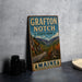 A vintage metal sign for Grafton Notch State Park in Maine, featuring a scenic mountain landscape.