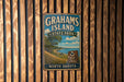 A vintage metal sign for Grahams Island State Park in North Dakota, featuring a scenic landscape with a lake and trees.