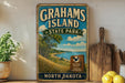 A vintage-style sign for Grahams Island State Park in North Dakota, featuring a scenic landscape with a lake and trees.