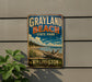 A vintage-style metal sign for Grayland Beach State Park in Washington, featuring a scenic landscape with a beach, mountains, and a cloudy sky.
