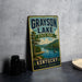 A vintage-style metal sign for Grayson Lake State Park in Kentucky, featuring a scenic image of the lake and surrounding landscape.
