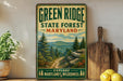 A vintage-style metal sign for the Green Ridge State Forest in Maryland, featuring a scenic mountain landscape with pine trees and a winding trail.