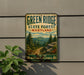 A vintage-style metal sign for Green Ridge State Forest in Maryland, featuring a scenic mountain landscape with pine trees and a winding trail.