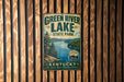 A vintage-style metal sign for Green River Lake State Park in Kentucky, featuring a scenic image of the lake surrounded by trees and mountains.