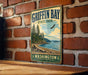A vintage metal sign for Griffin Bay State Park in Washington, featuring a scenic landscape with pine trees, a beach, and a bird in flight.