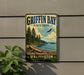 A vintage-style metal sign for the state park called "Griffin Bay" in Washington, featuring a scenic landscape with pine trees, a beach, and a bird in flight.