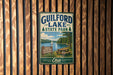 A vintage metal sign for Guilford Lake State Park in Ohio, featuring a scenic image of the lake and surrounding landscape.