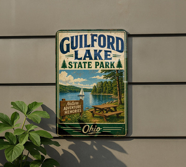 A vintage metal sign for Guilford Lake State Park, featuring a scenic image of a lake, trees, and a picnic table.