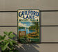 A vintage metal sign for Guilford Lake State Park, featuring a scenic image of a lake, trees, and a picnic table.