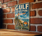 A vintage-style sign for Gulf State Park, Alabama, mounted on a brick wall.