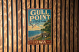 A vintage metal sign for Gull Point State Park in Iowa, featuring a scenic landscape with a beach, mountains, and a seagull in flight.