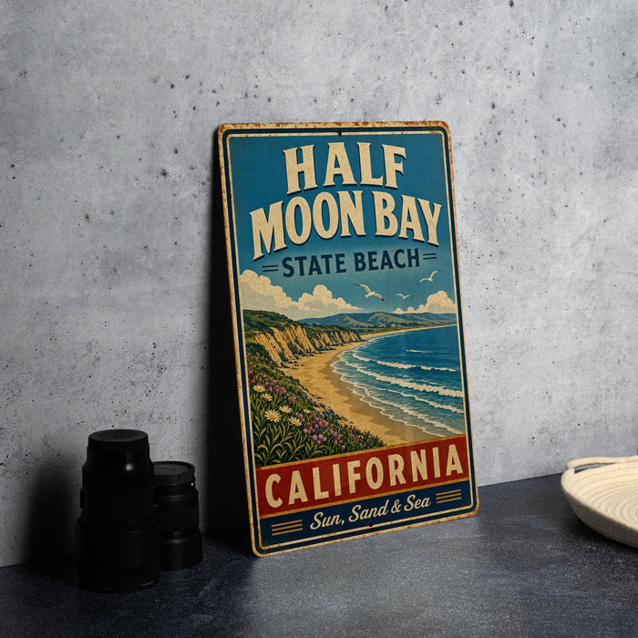 A vintage-style metal sign for Half Moon Bay State Beach in California, featuring a scenic illustration of the bay and coastline.