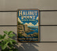A vintage metal sign for Halibut Point State Park in Massachusetts, featuring a scenic illustration of a rocky coastline with a sailboat in the distance.